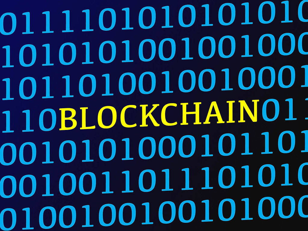 Blockchain text between blue binary data on screen